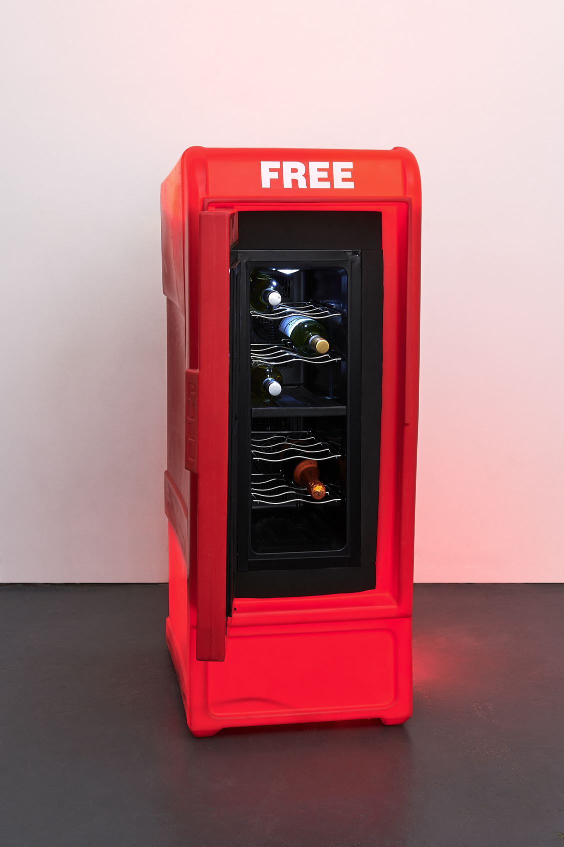a red refrigerator with bottles of wine inside. Carlo Sampietro