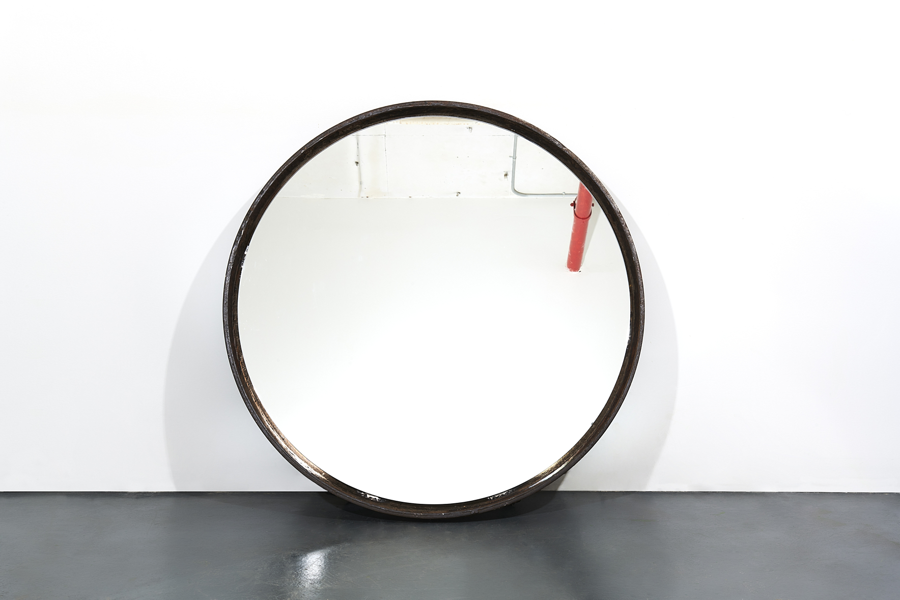 a round mirror on a white wall. Carlo Sampietro