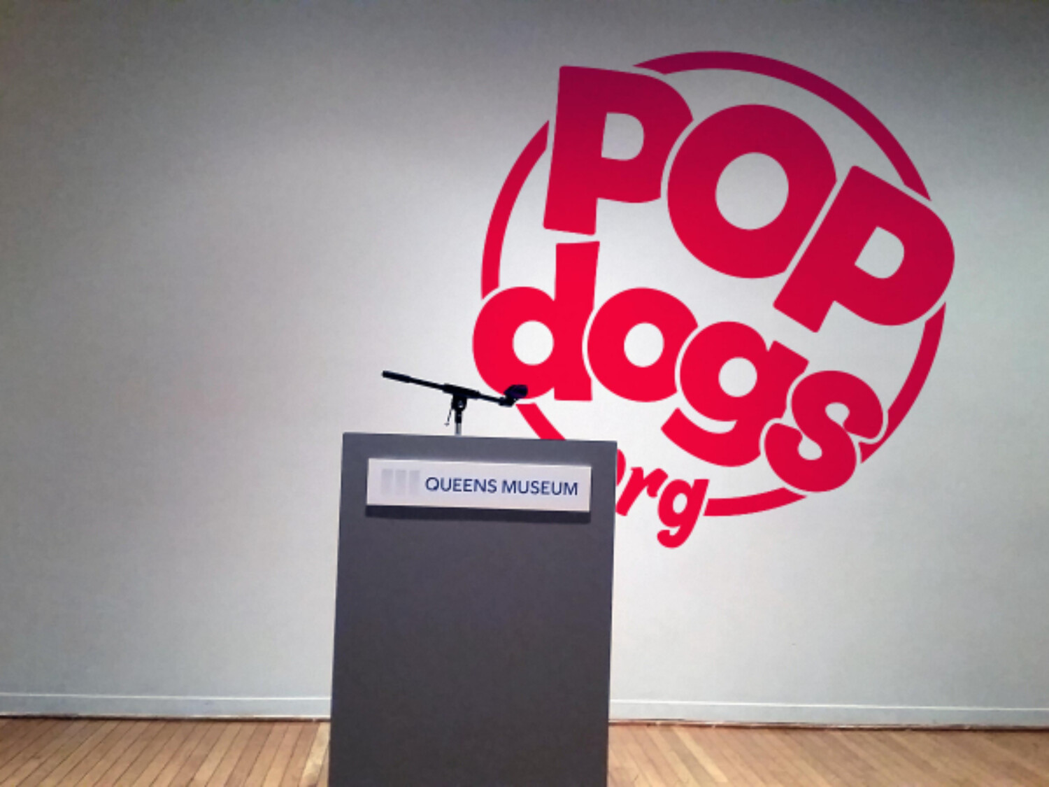 a podium with a microphone in front of a wall with red logo. Carlo Sampietro