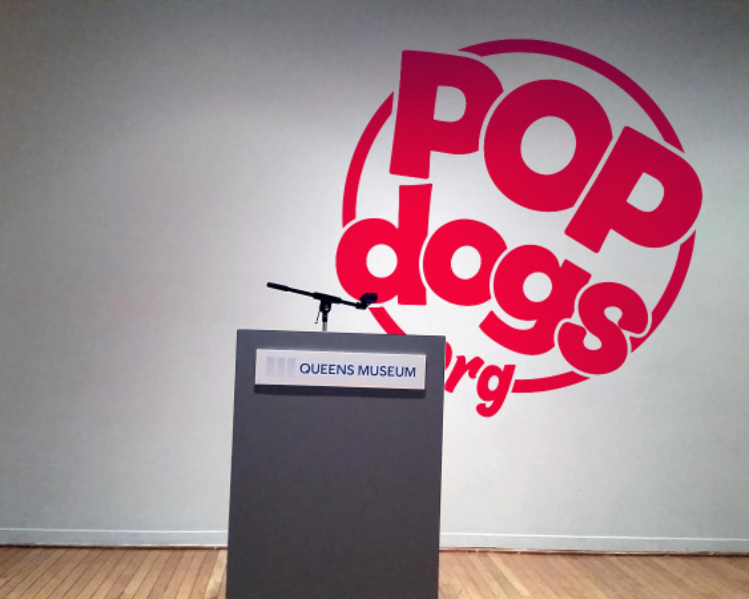 a podium with a microphone in front of a wall with red logo. Carlo Sampietro